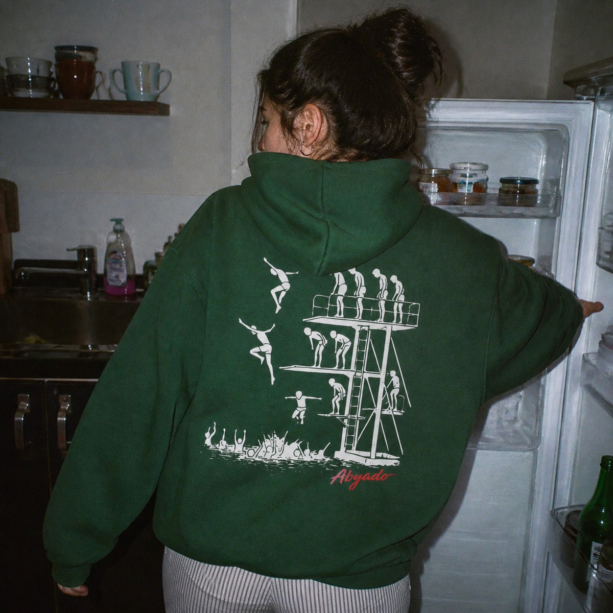Manhood Hoodie lifestyle — Pine Green back graphic — kitchen 1:1