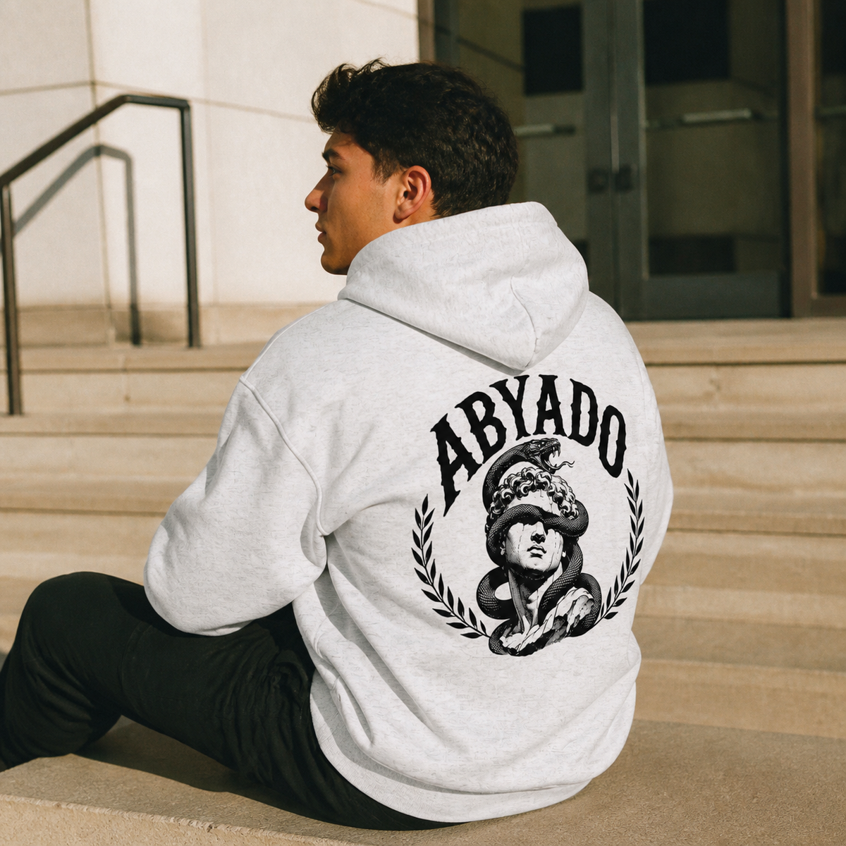 Relics Hoodie in White Heather, three-quarter back view on steps, film lifestyle photograph
