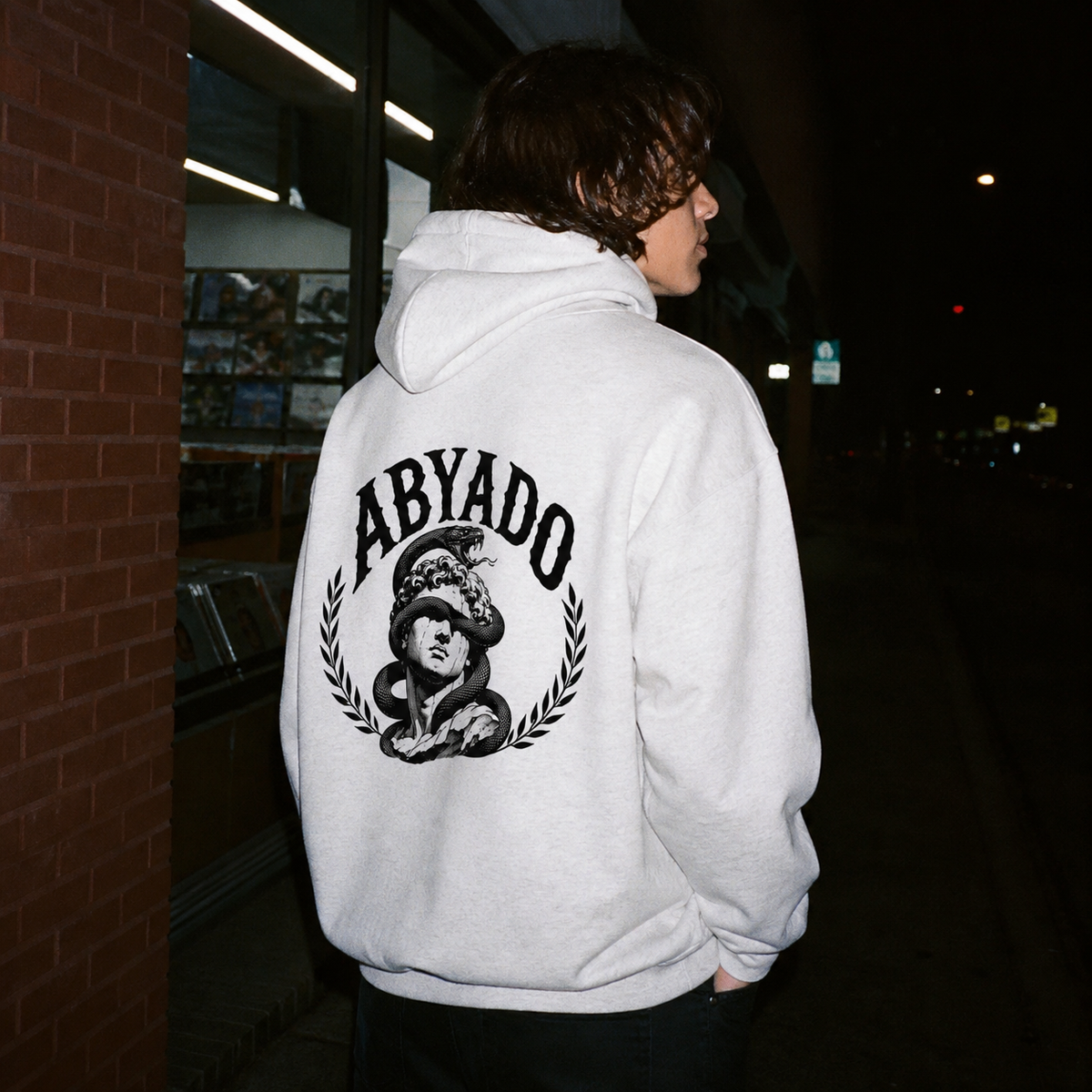 Relics Hoodie in White Heather, three-quarter back view at night, flash film lifestyle photograph